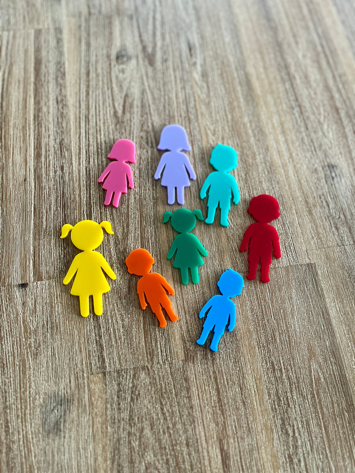 Eight colorful translucent child-shaped figures in various sizes arranged on a wood surface, Little Dry Erasables - People, handcrafted, homeschool, education resources.