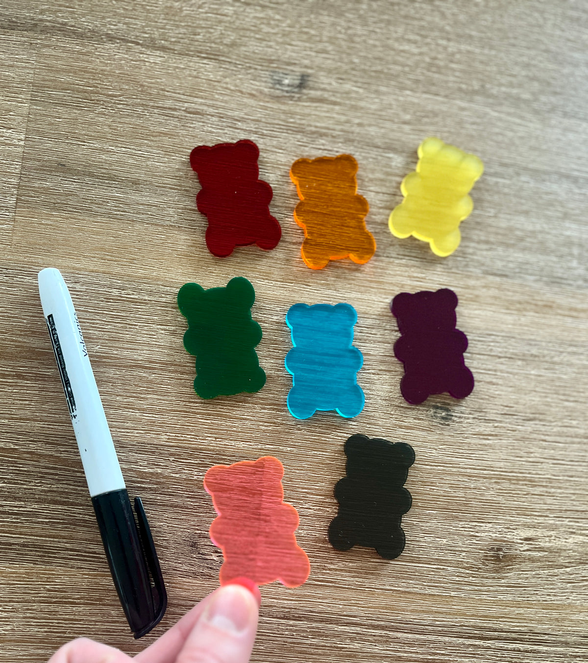 Little Dry Erasables — Gummy Bears featuring colorful translucent bear-shaped pieces in red, orange, yellow, green, blue, purple, pink, and black on a wood surface with a black marker, handcrafted homeschool education resources.