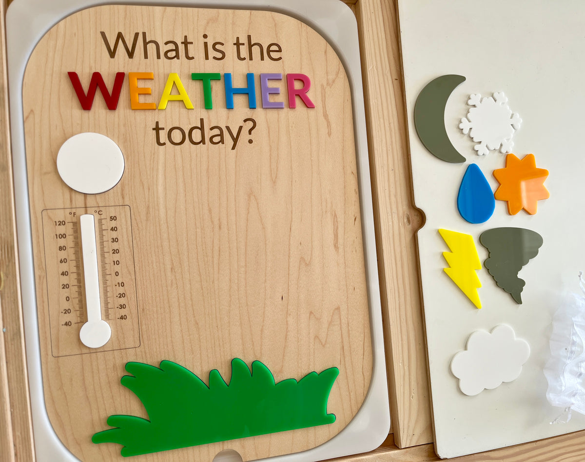 Wooden board with colorful letters spelling "weather" and magnetic weather symbol pieces including sun, cloud, rain, and lightning