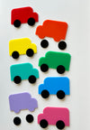 Eight colorful abstract toy trucks in red, orange, yellow, green, teal, blue, purple, and pink with separate black wheels on white background