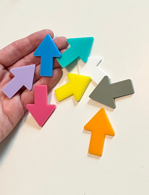 Colorful arrow-shaped dry erase shapes held in a hand on a light background