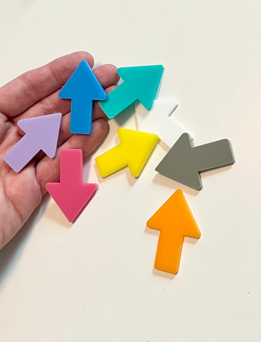 Colorful arrow-shaped dry erase shapes held in a hand on a light background