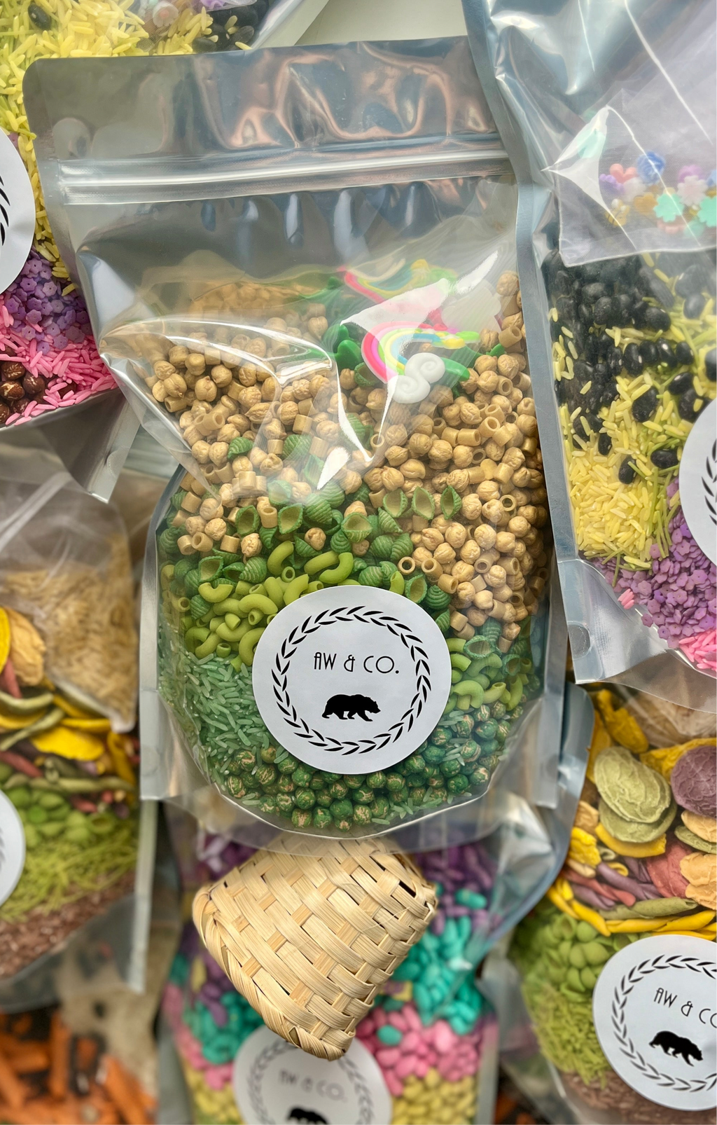 Clear resealable bag with green pasta, wooden beads, and small rainbow and cloud shapes inside and around it