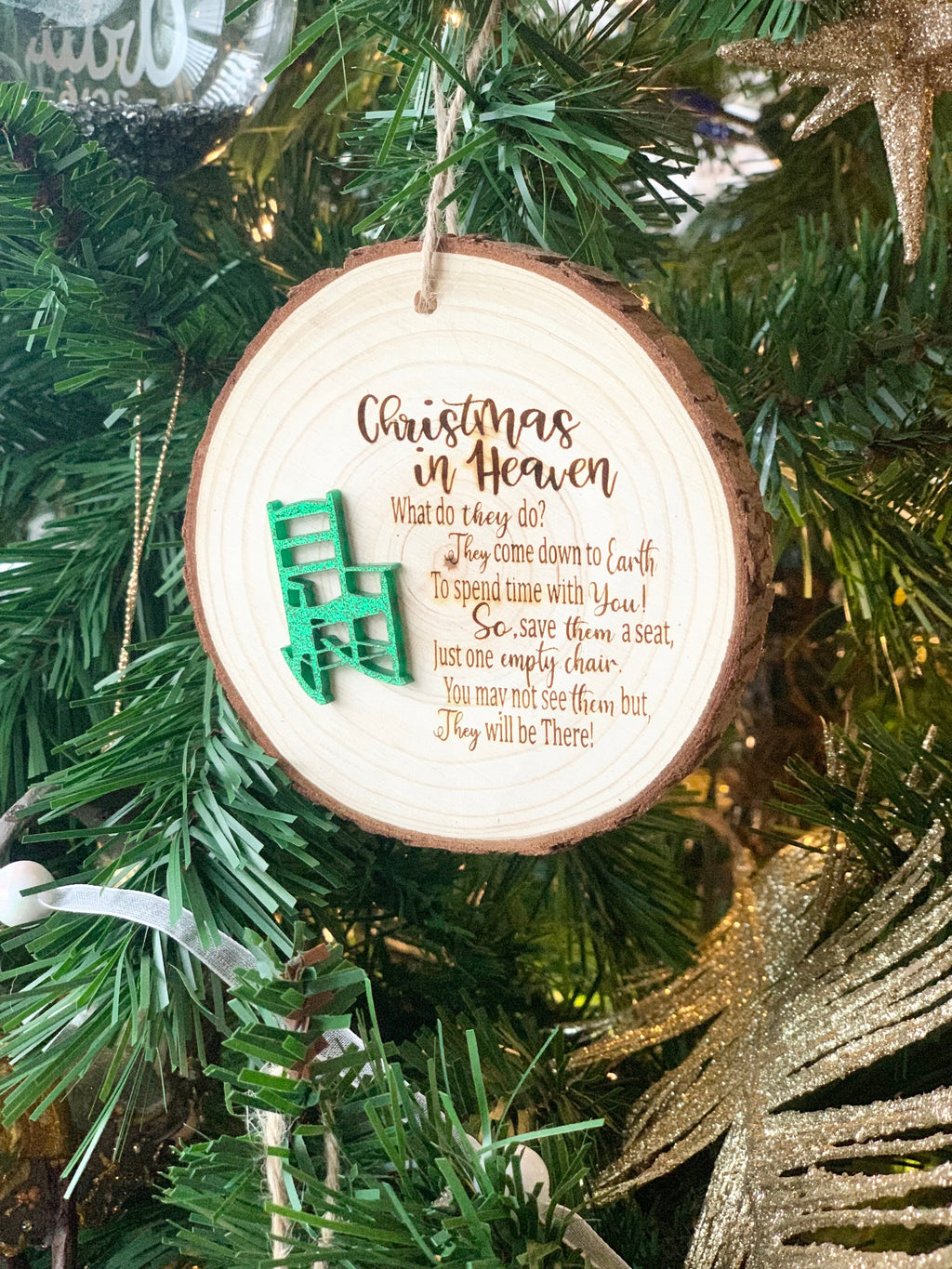 Round wooden Christmas ornament with green miniature chair and memorial poem hanging on tree branch