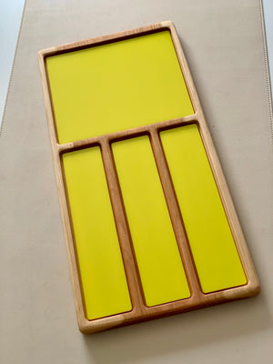 Wooden organizer tray with one large square and three narrow rectangular yellow panels on a beige background