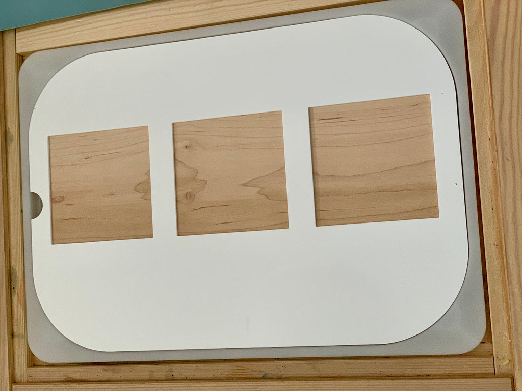 White board with three rectangular wooden shapes of varying sizes arranged horizontally on a wooden surface