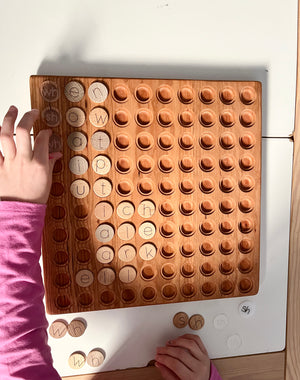 Wooden 100 Hundred Board Tray | Counting & Number Sense Learning Tray | Combos Available showing a child placing round letter tokens on a handcrafted wood tray with circular slots, unique homeschool education resources.