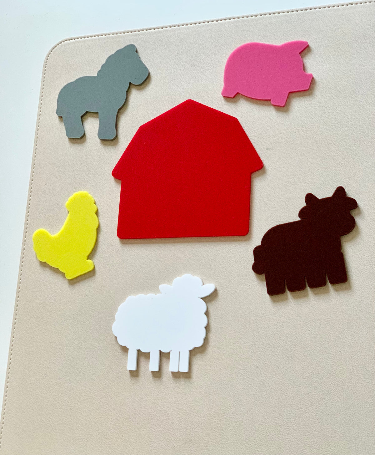 Colorful foam barn shape surrounded by foam farm animals including horse, pig, chicken, cow, and sheep on beige surface