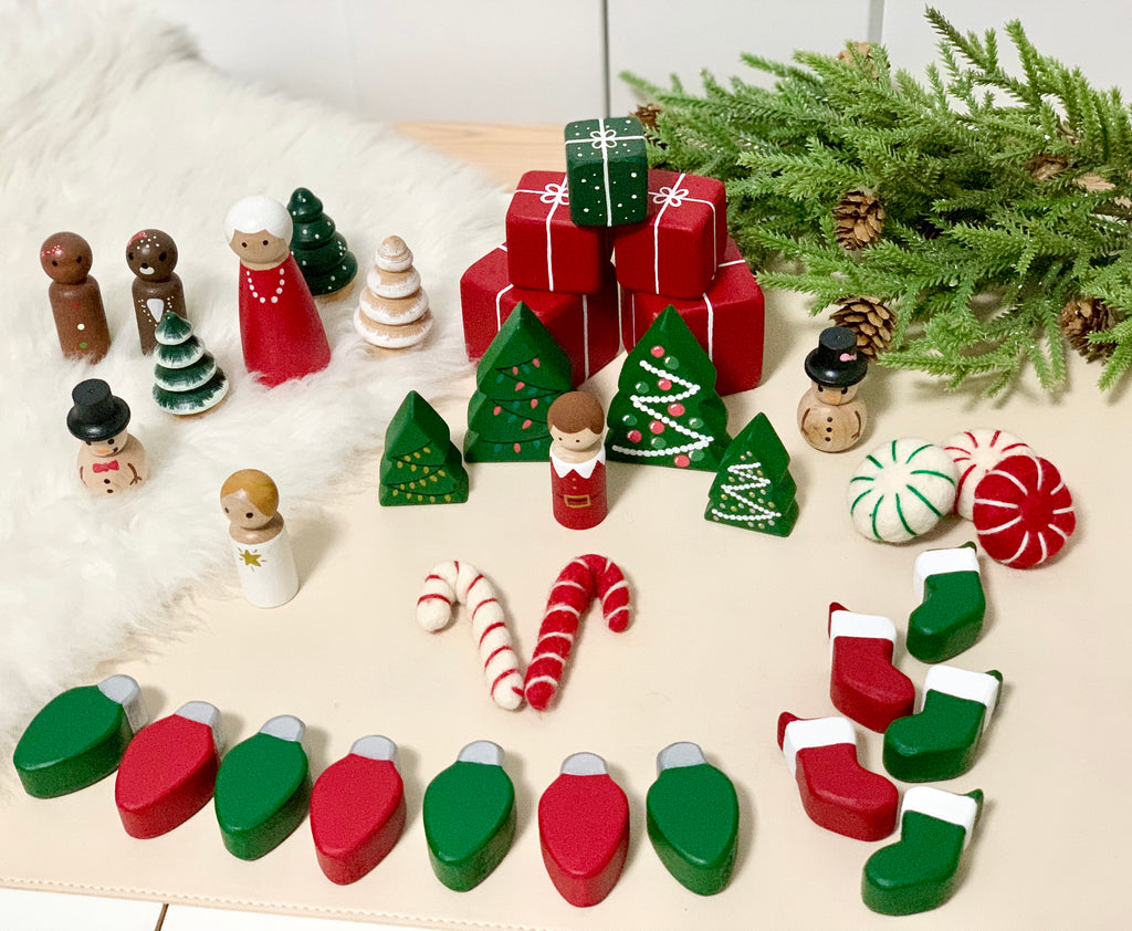 Set of 5 wooden Christmas light bulbs and stockings with holiday peg dolls, trees, candy canes, and wrapped presents on table
