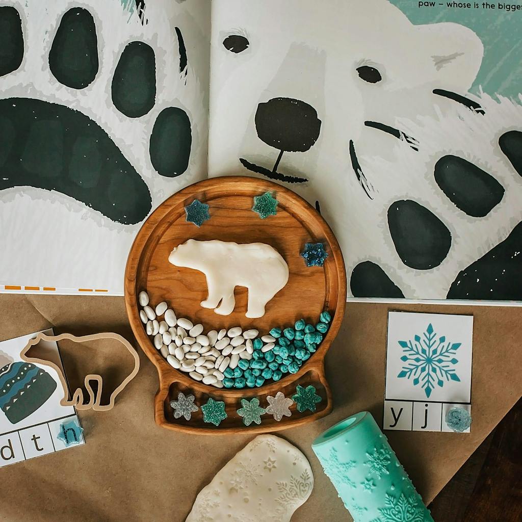 Round wooden sensory tray shaped like a snow globe with polar bear, white and blue stones, and snowflake decorations