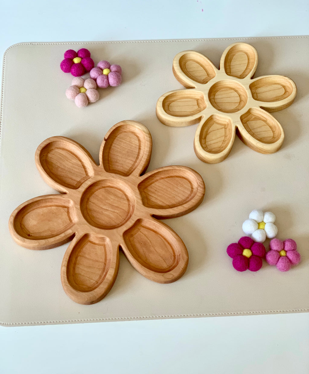 Two wooden flower-shaped trays with six petal compartments each surrounded by small colorful felt flower decorations