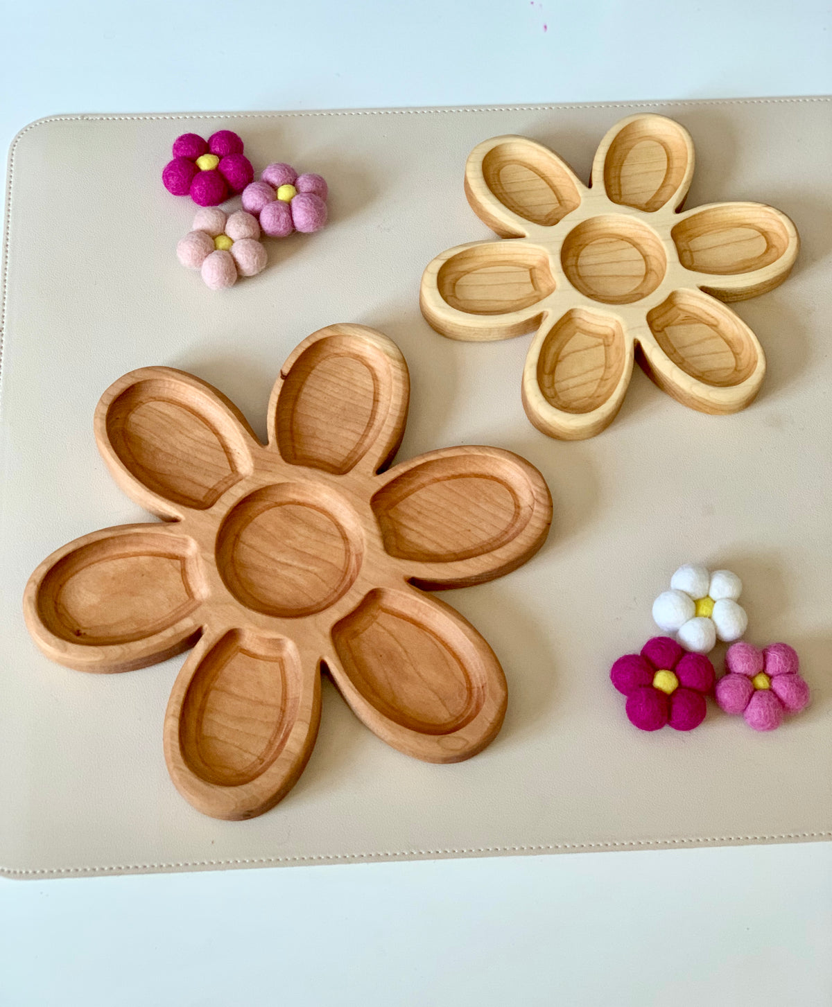 Two wooden flower-shaped trays with six petal compartments each surrounded by small colorful felt flower decorations