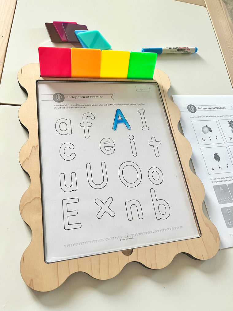Wooden-framed dry erase board with alphabet practice sheet and colorful translucent magnetic squares on top