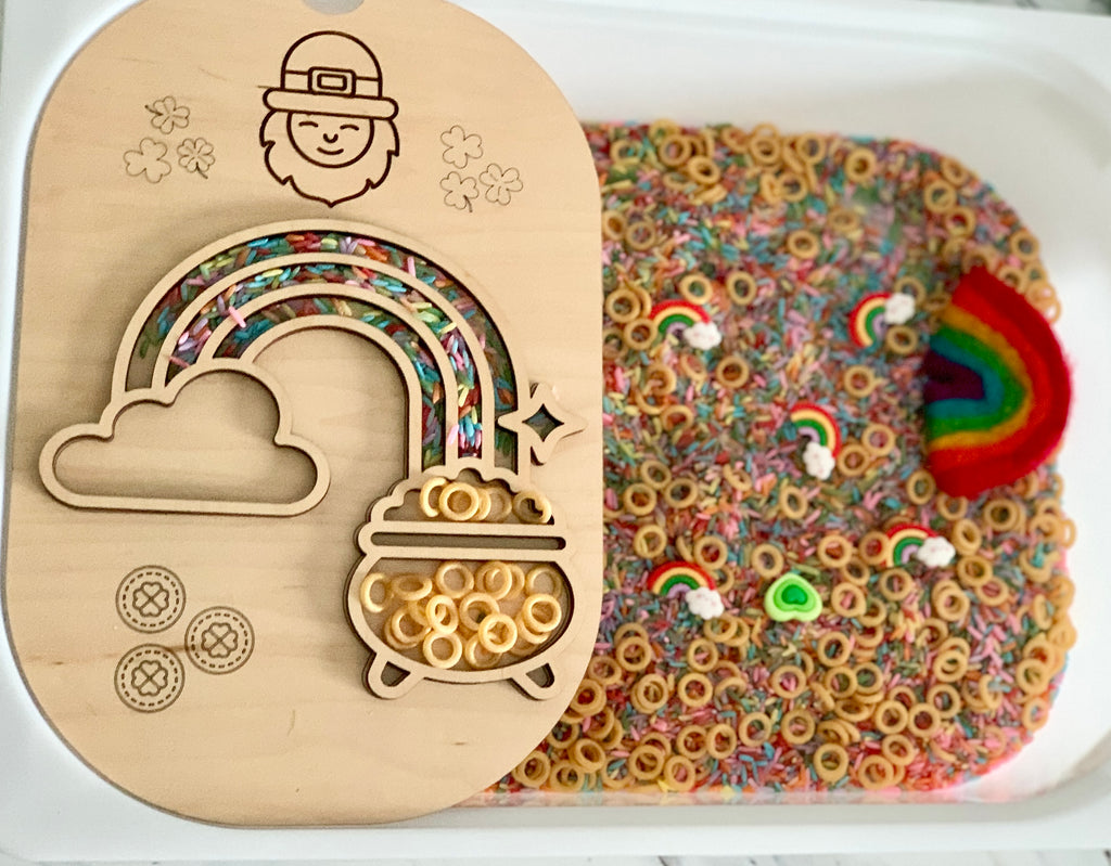 Wooden rainbow and pot of gold tray with Cheerios, colorful rice, rainbow and shamrock shapes in sensory bin