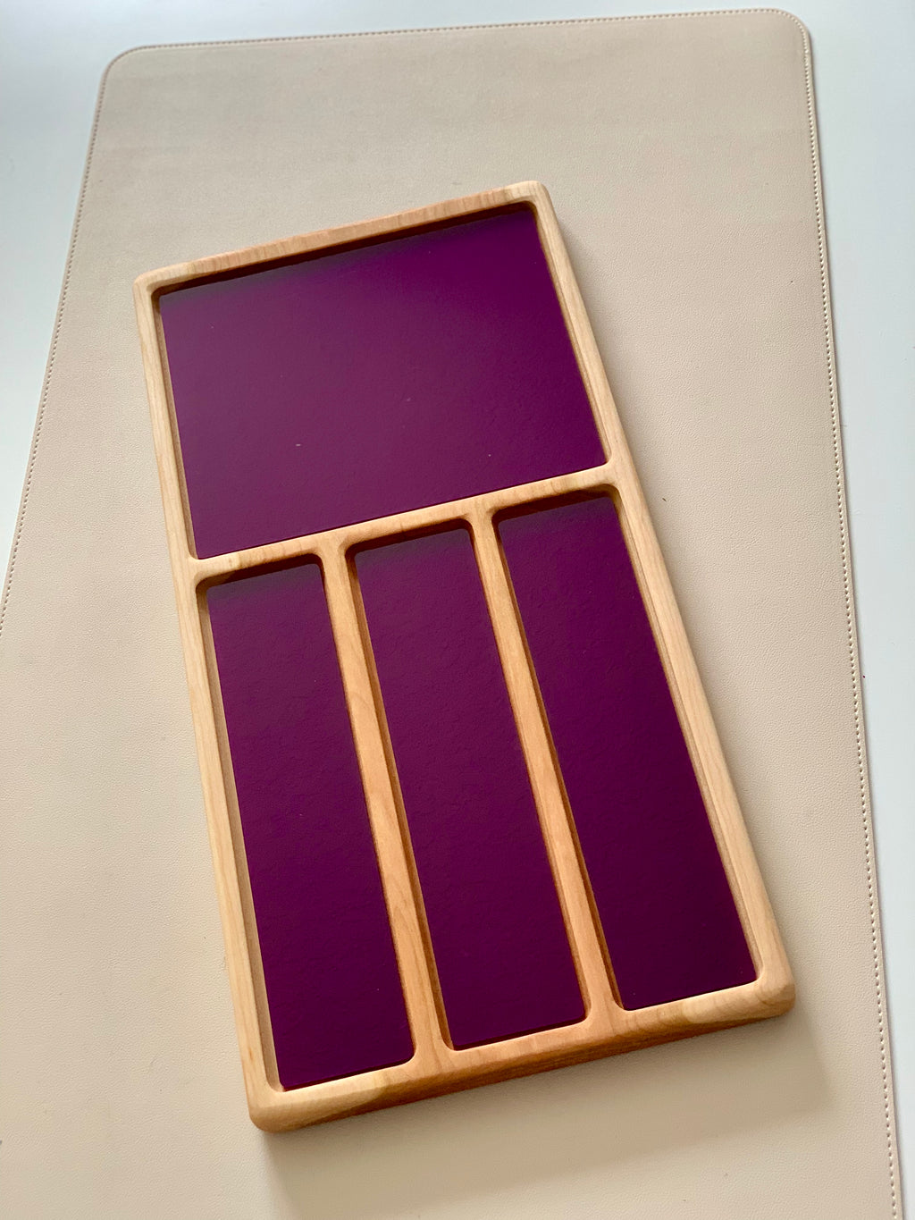 Wooden tray with one large square and three narrow vertical compartments featuring dark purple panels on a light surface