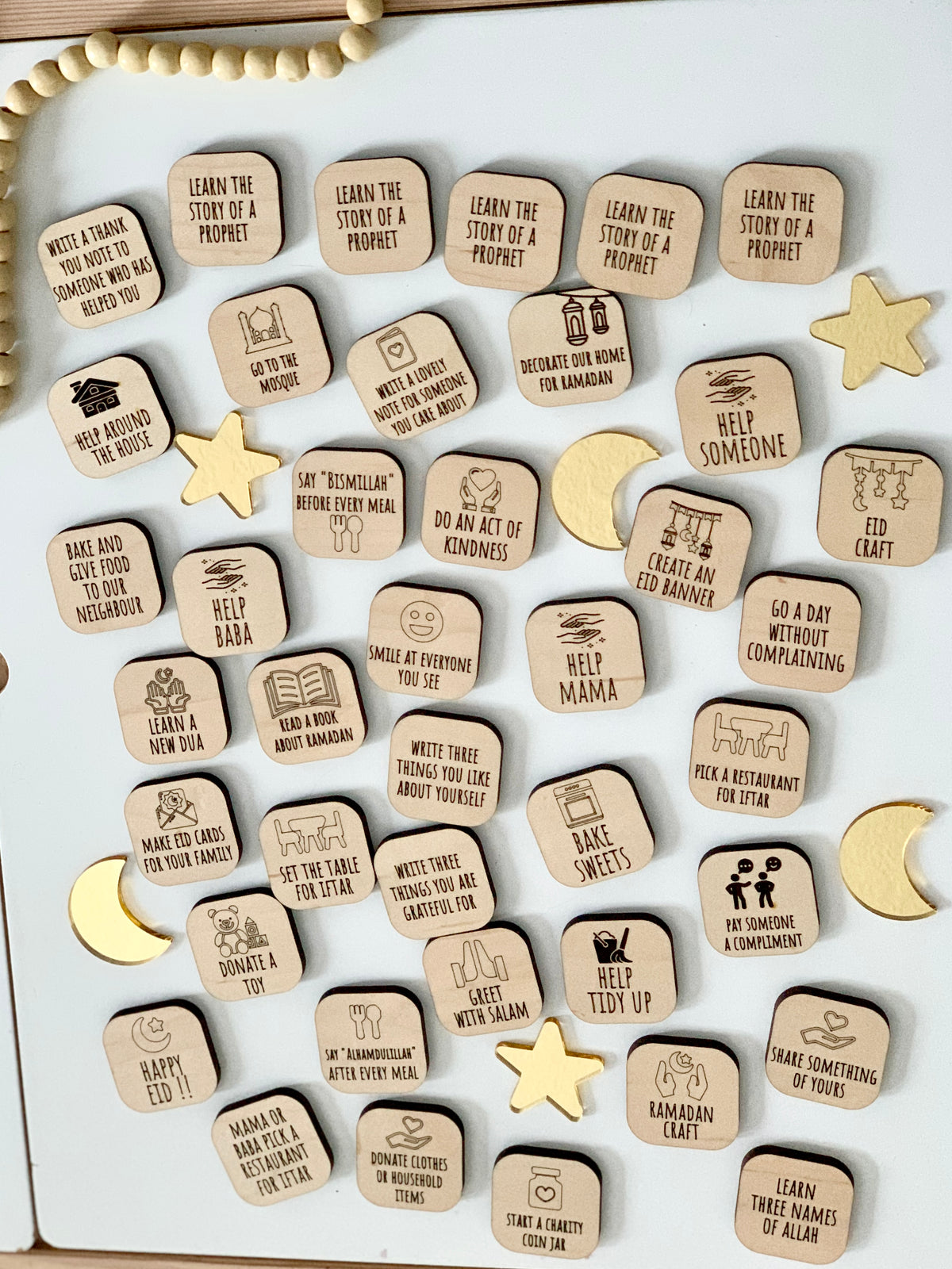 Wooden activity tiles with Ramadan-themed tasks and icons scattered on a white surface with wooden stars and crescent moons
