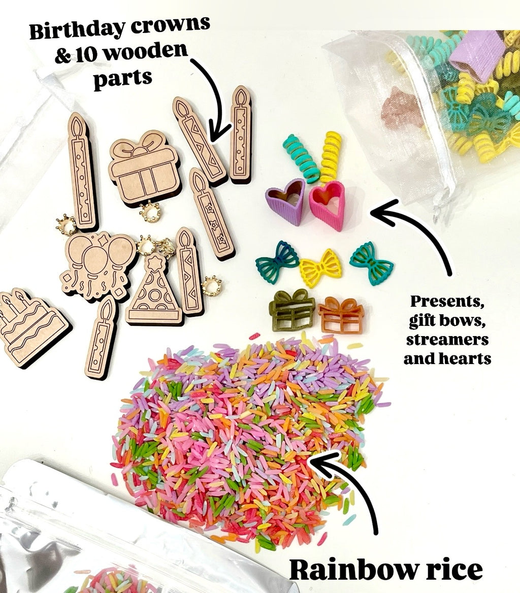 Assorted wooden birthday shapes, colorful gift bows, hearts, streamers, and multicolored rainbow rice on white surface