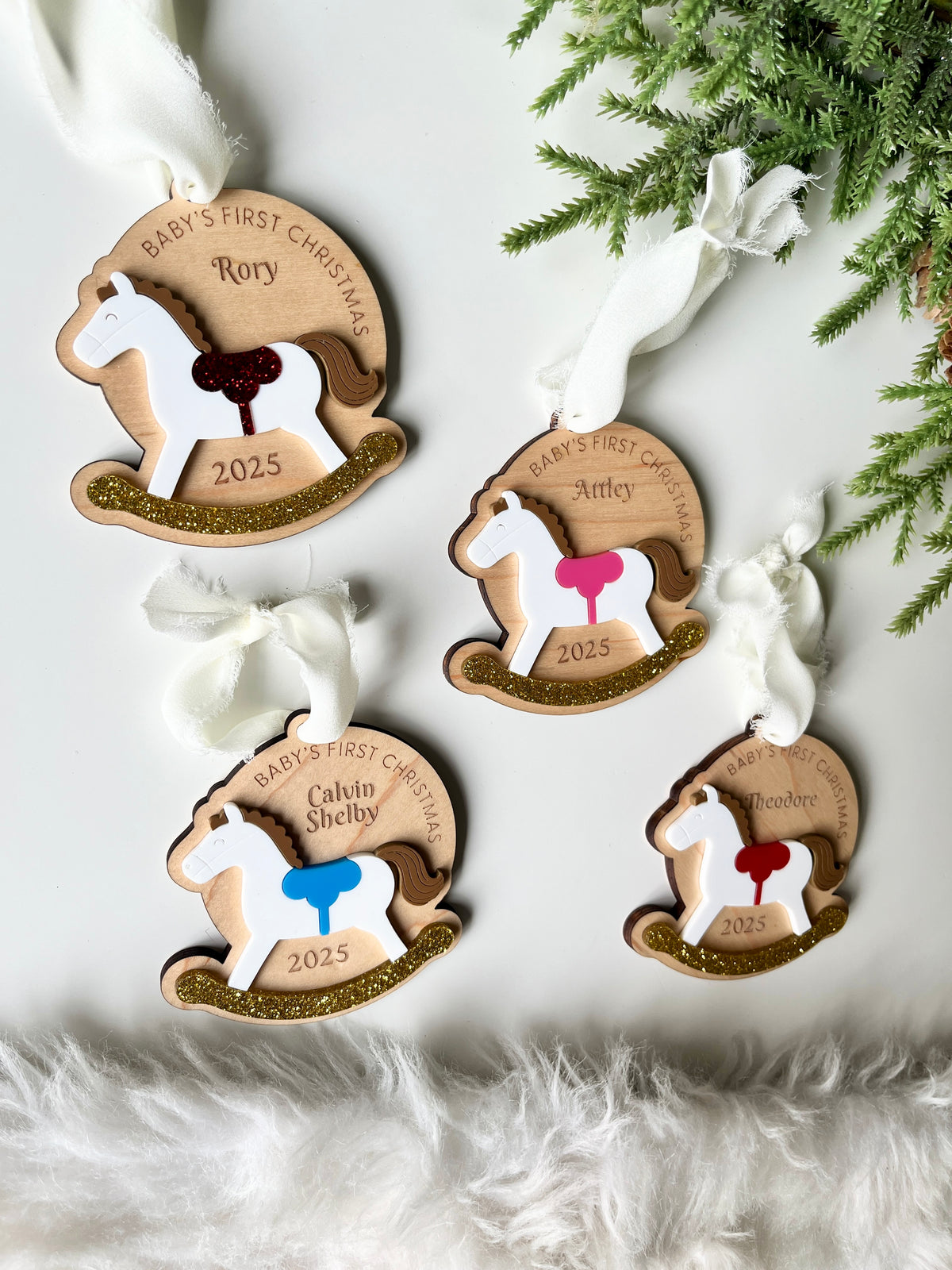 Four wooden rocking horse ornaments with personalized names, colorful saddles, and gold glitter details on white background