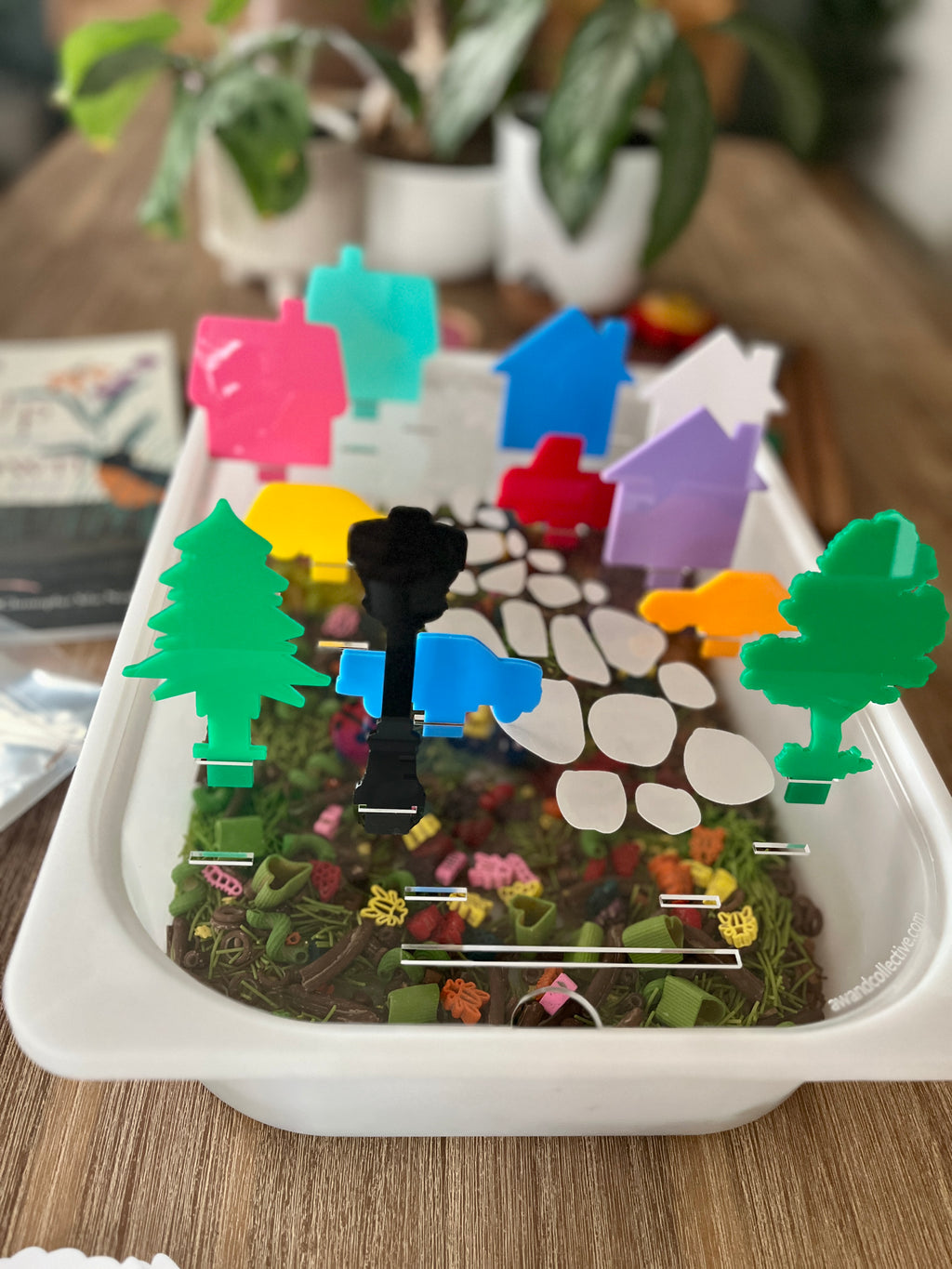 White tray with a garden and stone path design holding colorful translucent acrylic pegs shaped like trees and houses, showcasing STEM Insert – Acrylic Insert with Different Peg Options - Neighborhood, Veggie Garden, Flower Garden, Under the Sea + More, handcrafted, homeschool, education resources.