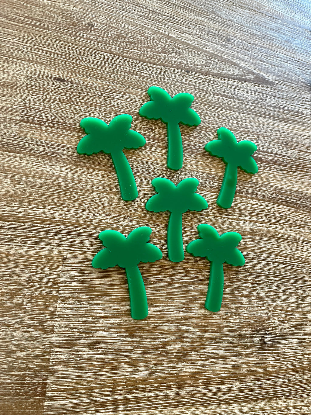 Six small green palm tree shapes made of durable material arranged on a wooden surface, Little Dry Erasables - Palm Trees, handcrafted, homeschool, education resources.