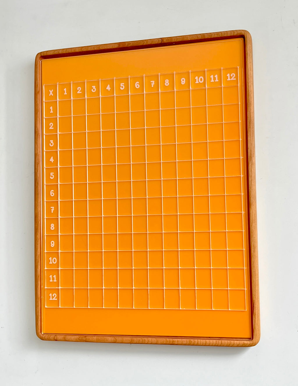 Orange multiplication grid board with wooden frame and clear numbered squares from 1 to 12