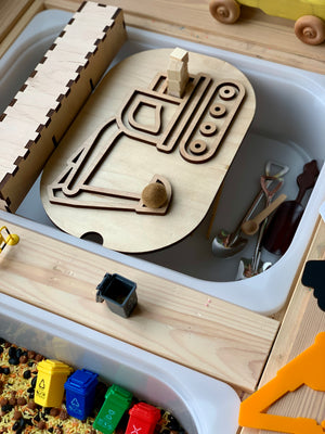 Wooden excavator puzzle piece placed inside a white container surrounded by small toy tools and colorful toy recycling bins nearby