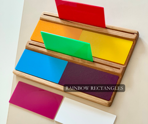 Wooden board holding colorful rectangular panels in red, orange, yellow, green, blue, purple, magenta, and white on a light surface