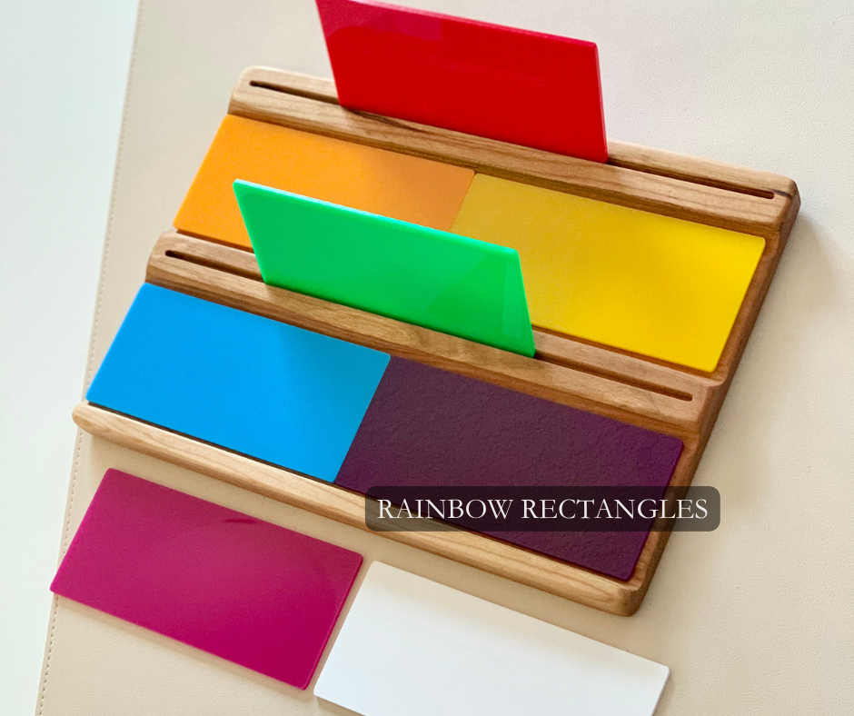 Wooden board holding colorful rectangular panels in red, orange, yellow, green, blue, purple, magenta, and white on a light surface
