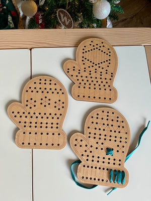 Three Mitten Lacing Boards made of wood with patterned holes, one partially threaded with blue lacing, handcrafted homeschool educational resources for fine motor skills development.