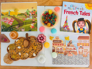 Cloud-shaped wooden sensory tray filled with dry materials and surrounded by colorful toys and children's books on table