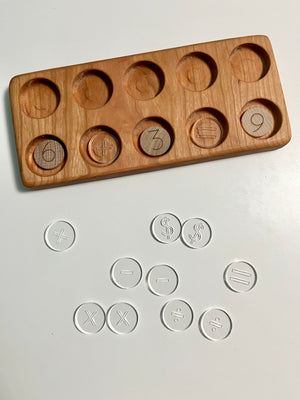 Mini Wood or Clear Acrylic Math Symbol Discs showing a wooden tray with circular slots containing numbers and math symbols, alongside clear acrylic discs featuring engraved arithmetic marks, handcrafted homeschool education resources promoting tactile and sensory learning.