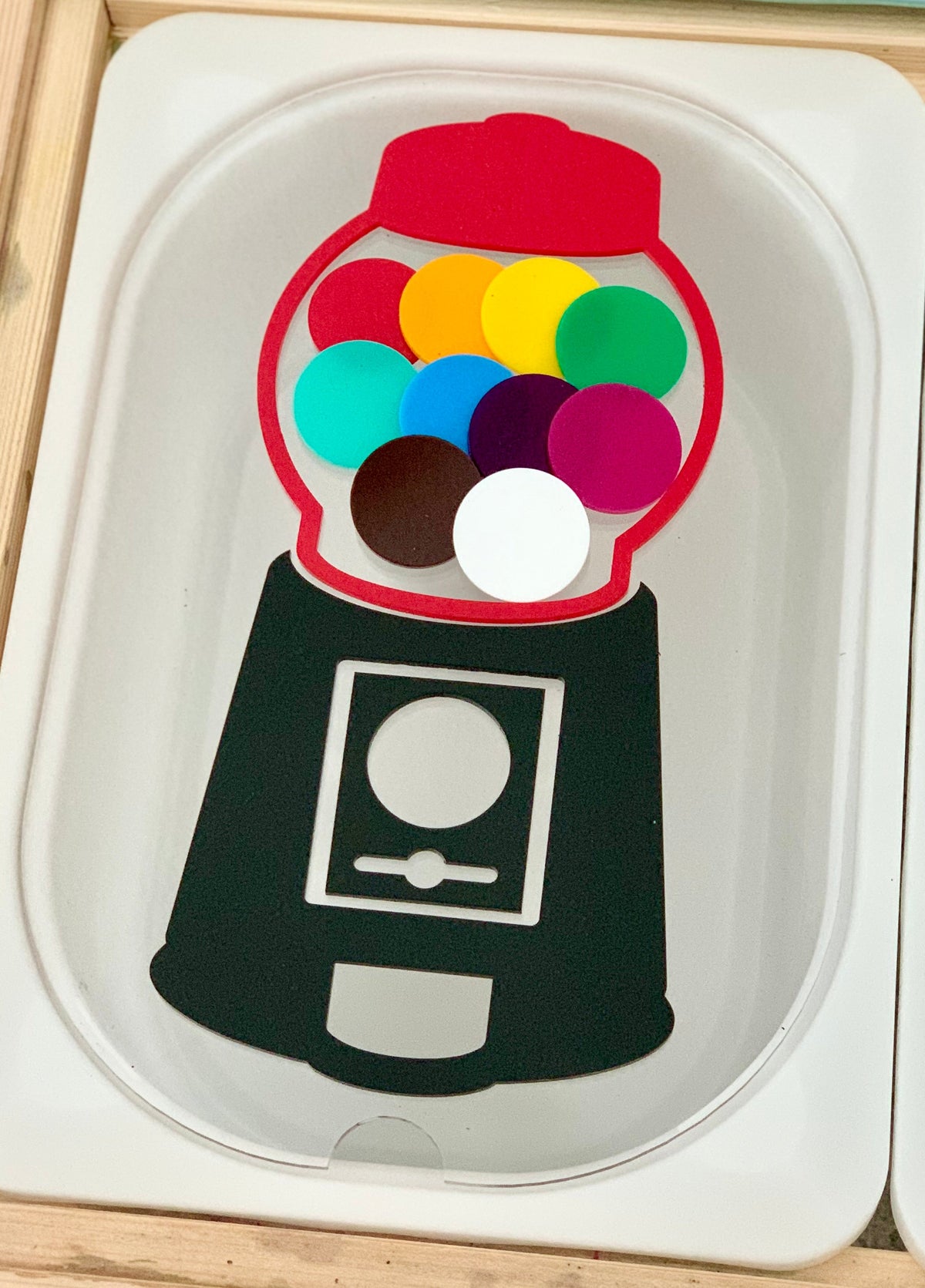 Illustration of a gumball machine filled with colorful round tokens on a white tray surface