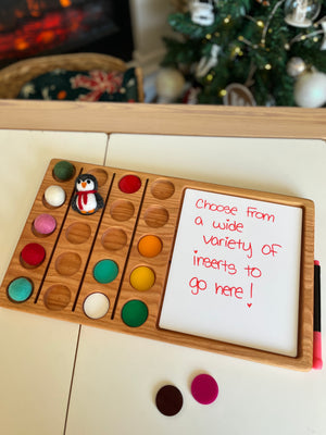 Wooden board with colorful felt balls and a small penguin figure beside whiteboard with red handwriting marker