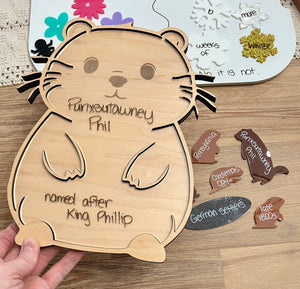Laser Cut Groundhog Tray with Dry Erase Insert shaped like a groundhog with handwritten notes, surrounded by wood pieces labeled with historical and cultural terms, handcrafted homeschool education resources.