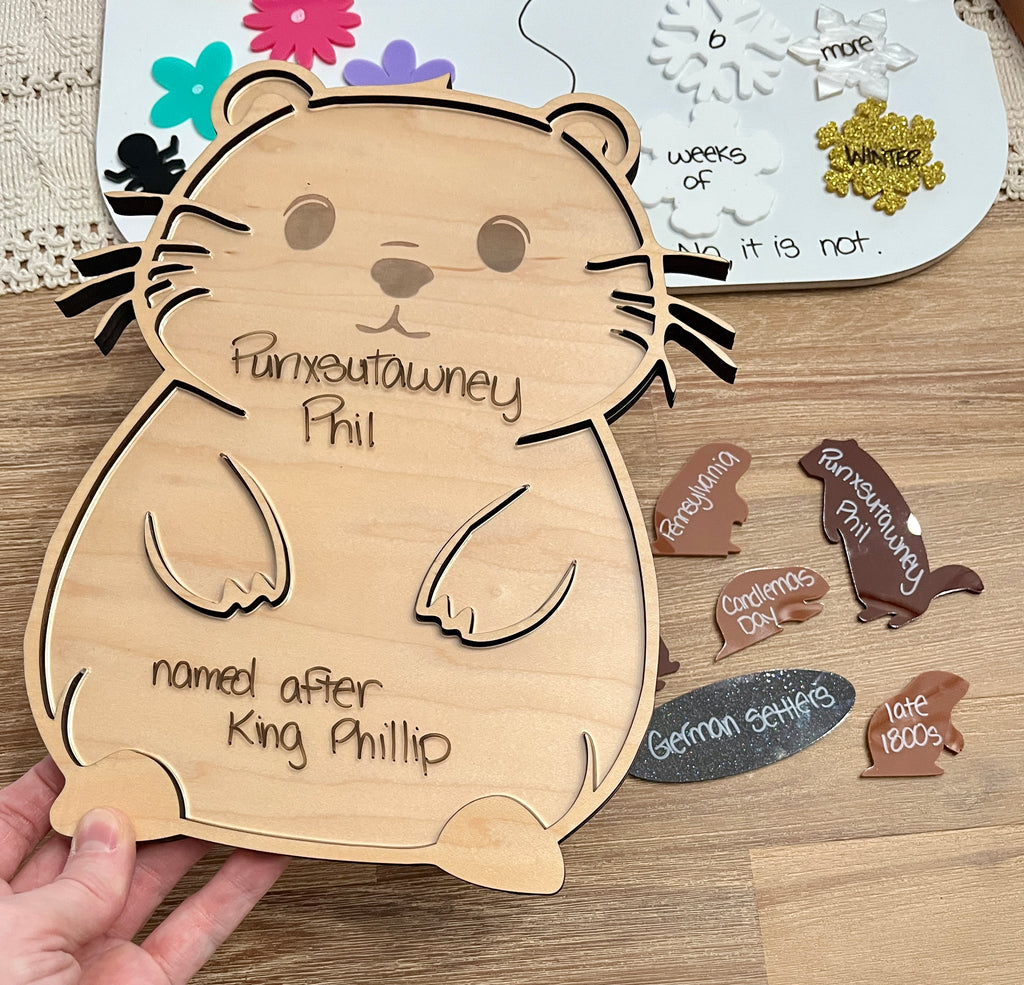 Laser Cut Groundhog Tray with Dry Erase Insert shaped like a groundhog with handwritten notes, surrounded by wood pieces labeled with historical and cultural terms, handcrafted homeschool education resources.
