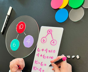 Acrylic Dry Erasable Multi-Use Circle Bond Graphic Organizer with colorful discs arranged on a clear board and a child using a dry erase marker to write math equations on a whiteboard, handcrafted homeschool educational resources.