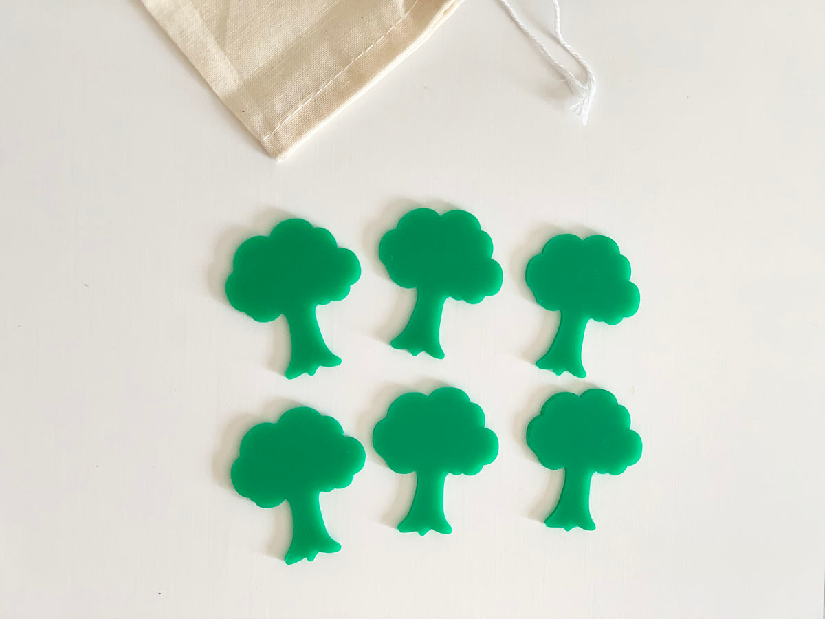 Set of six small green tree-shaped dry erasable boards with rounded edges on white background and cloth bag edge visible