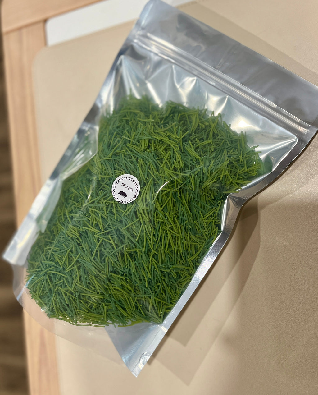 Transparent resealable bag filled with fresh green pine needles placed on a beige surface