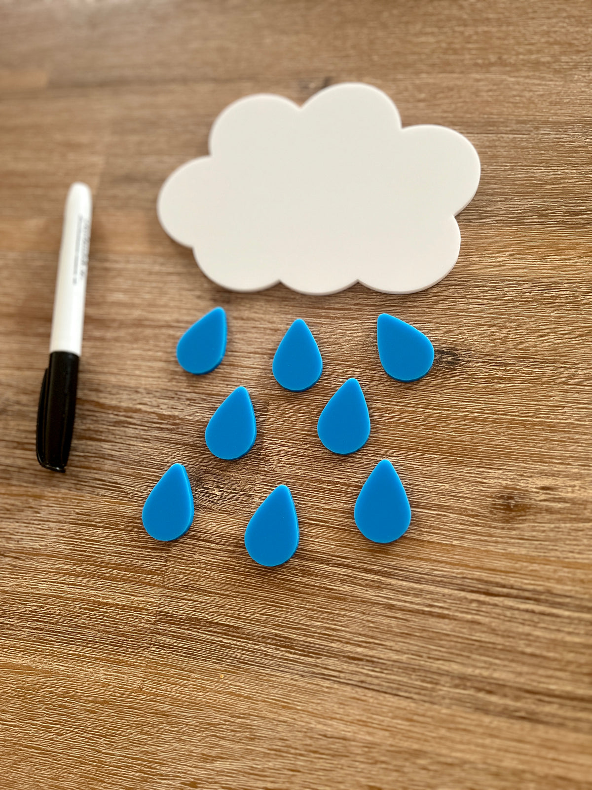 Little Dry Erasables - Cloud with Raindrops featuring a handcrafted white cloud shape with blue raindrop pieces and a black dry erase marker on a wooden surface, homeschool educational resources.