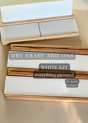 White dry erase panels with wooden frames arranged on a beige surface without any boards included in the image