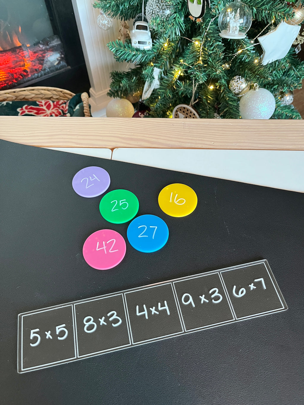 Black writing surface with multiplication problems in white squares and colorful round discs displaying answers nearby