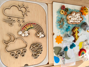 Wooden board with weather-themed cutouts of cloud, sun, raindrops, rainbow, snowflakes, and tornado shape filled with colorful beads and pasta shapes