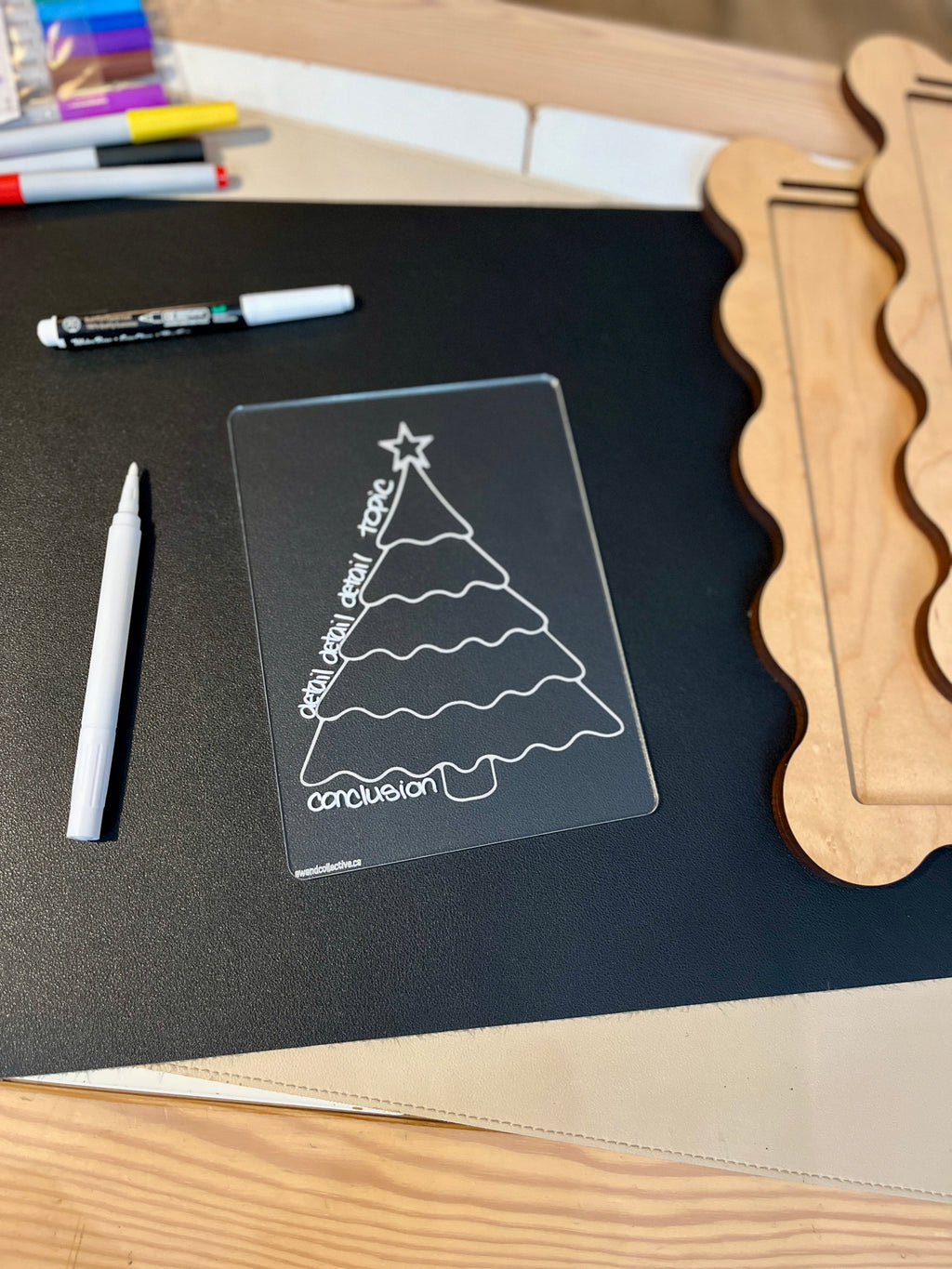 Clear plastic overlay with Christmas tree design labeled with topic, detail, detail, detail, and conclusion on black surface