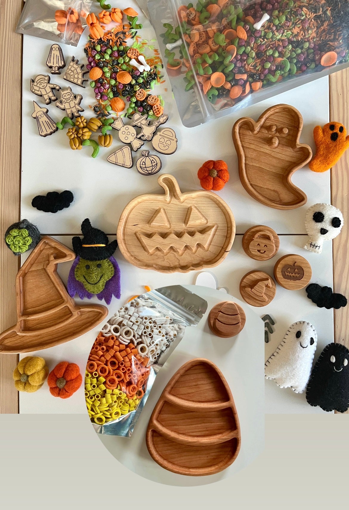 Wooden Halloween-themed trays shaped like pumpkin, ghost, witch hat, and candy corn surrounded by felt decorations and craft supplies