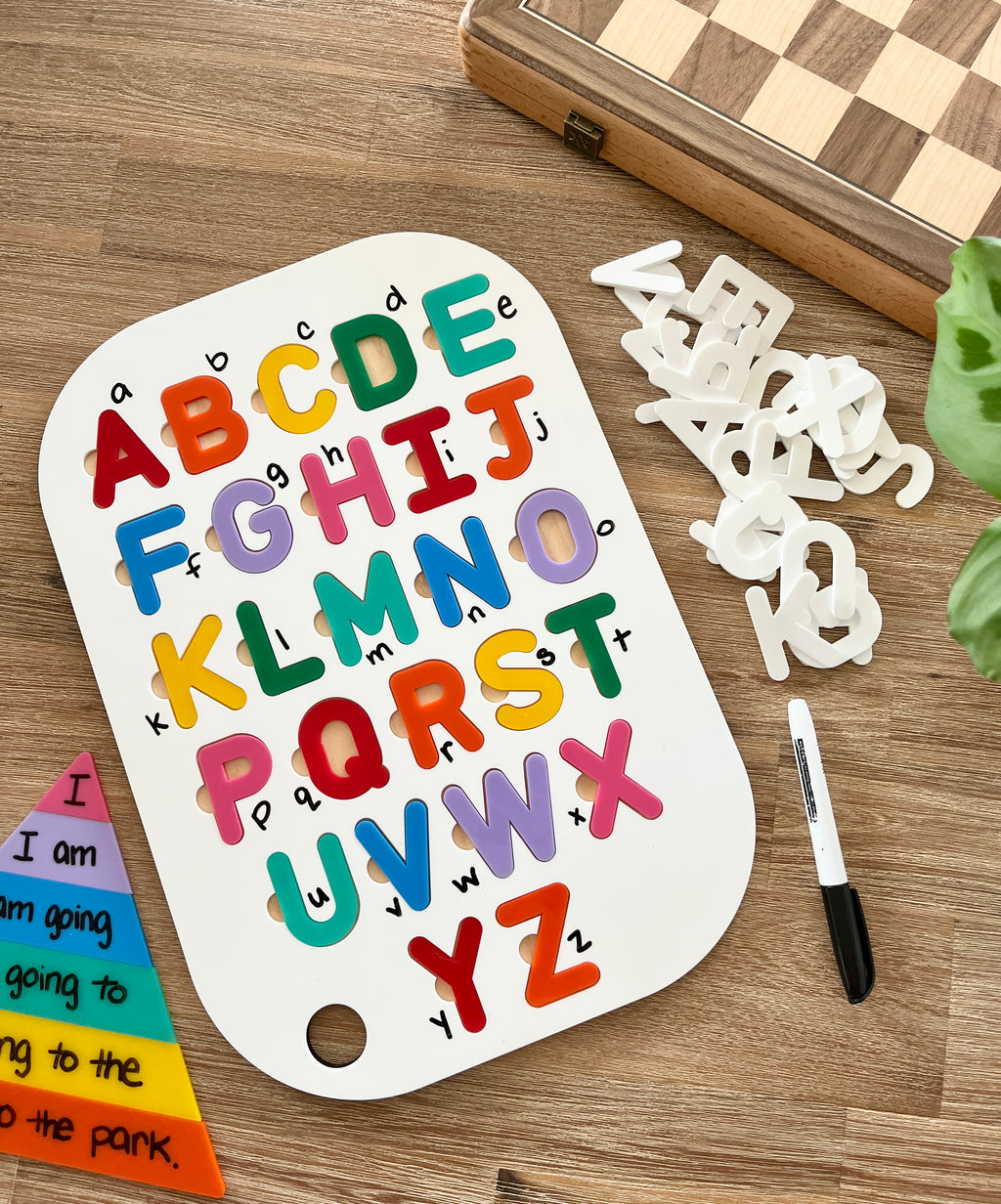 Acrylic Dry Erase Uppercase Alphabet Puzzle Flisat Table Top Insert with Both Rainbow and White Letters on a wooden surface, colorful uppercase letters on white insert, black dry erase marker, handcrafted homeschool education resources.