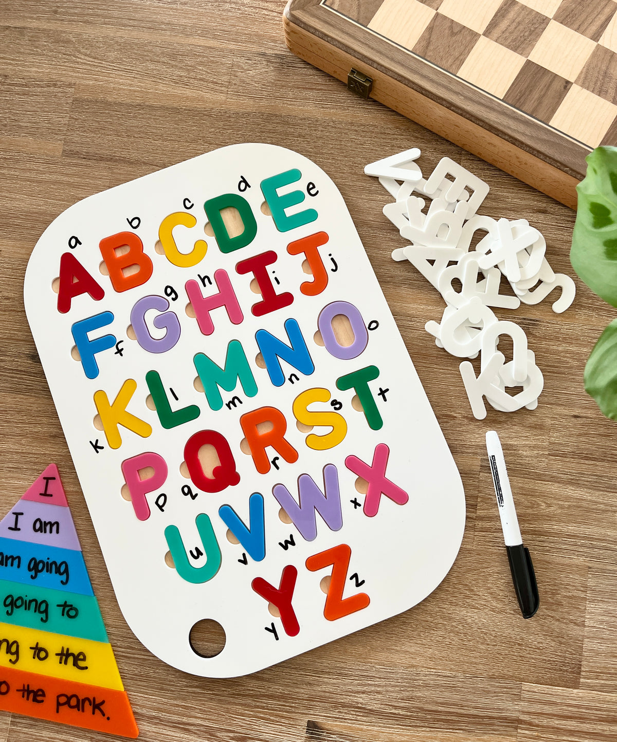Acrylic Dry Erase Uppercase Alphabet Puzzle Flisat Table Top Insert with Both Rainbow and White Letters on a wooden surface, colorful uppercase letters on white insert, black dry erase marker, handcrafted homeschool education resources.