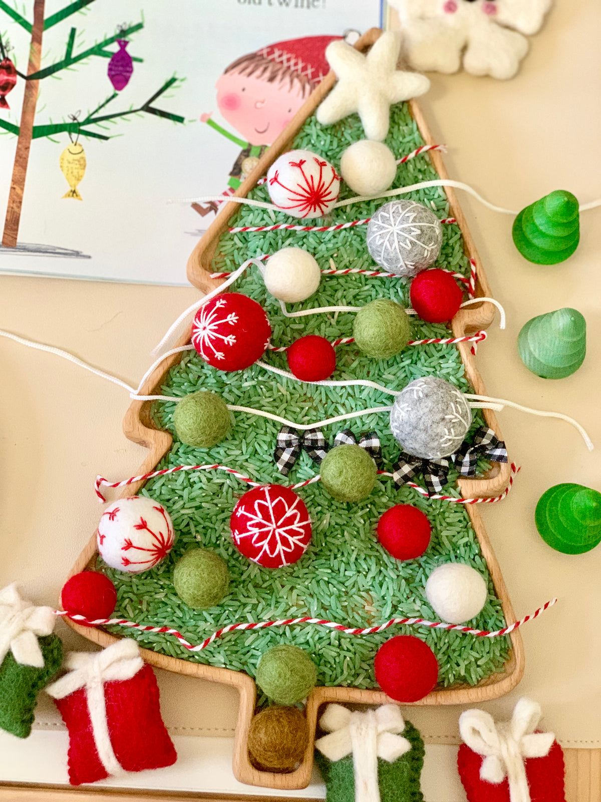 Large wooden tree-shaped plate filled with green rice and decorated with red, white, and green felt balls and string