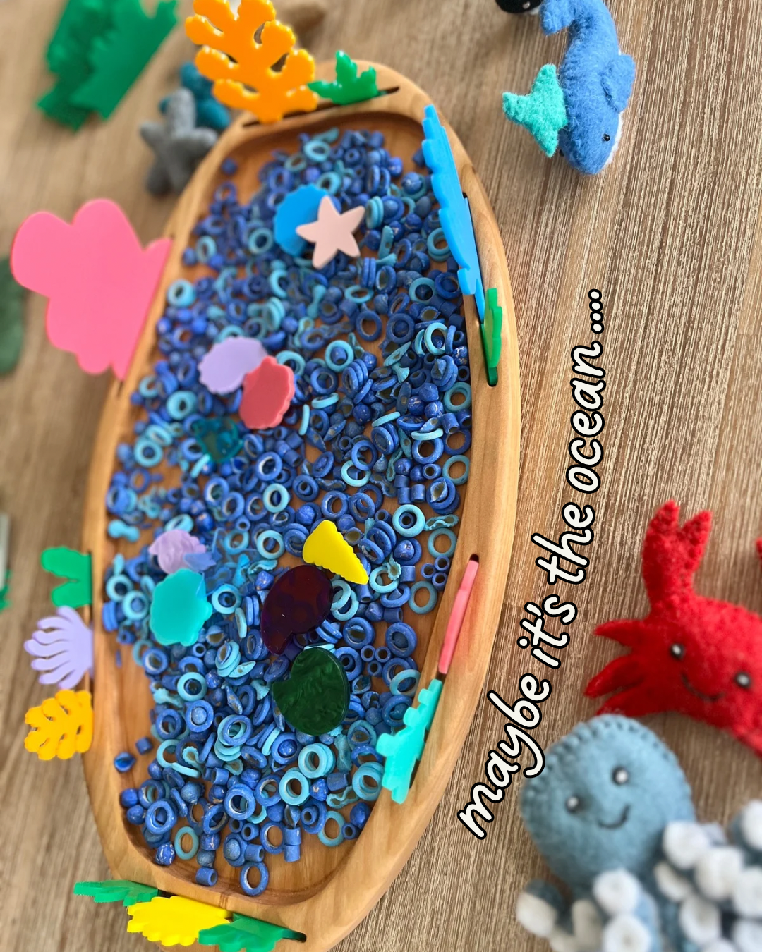 Multipurpose Oval Sensory Tray filled with blue ring sensory fillers and colorful ocean-themed felt shapes, surrounded by plush sea creature figures, handcrafted, homeschool, education resources.