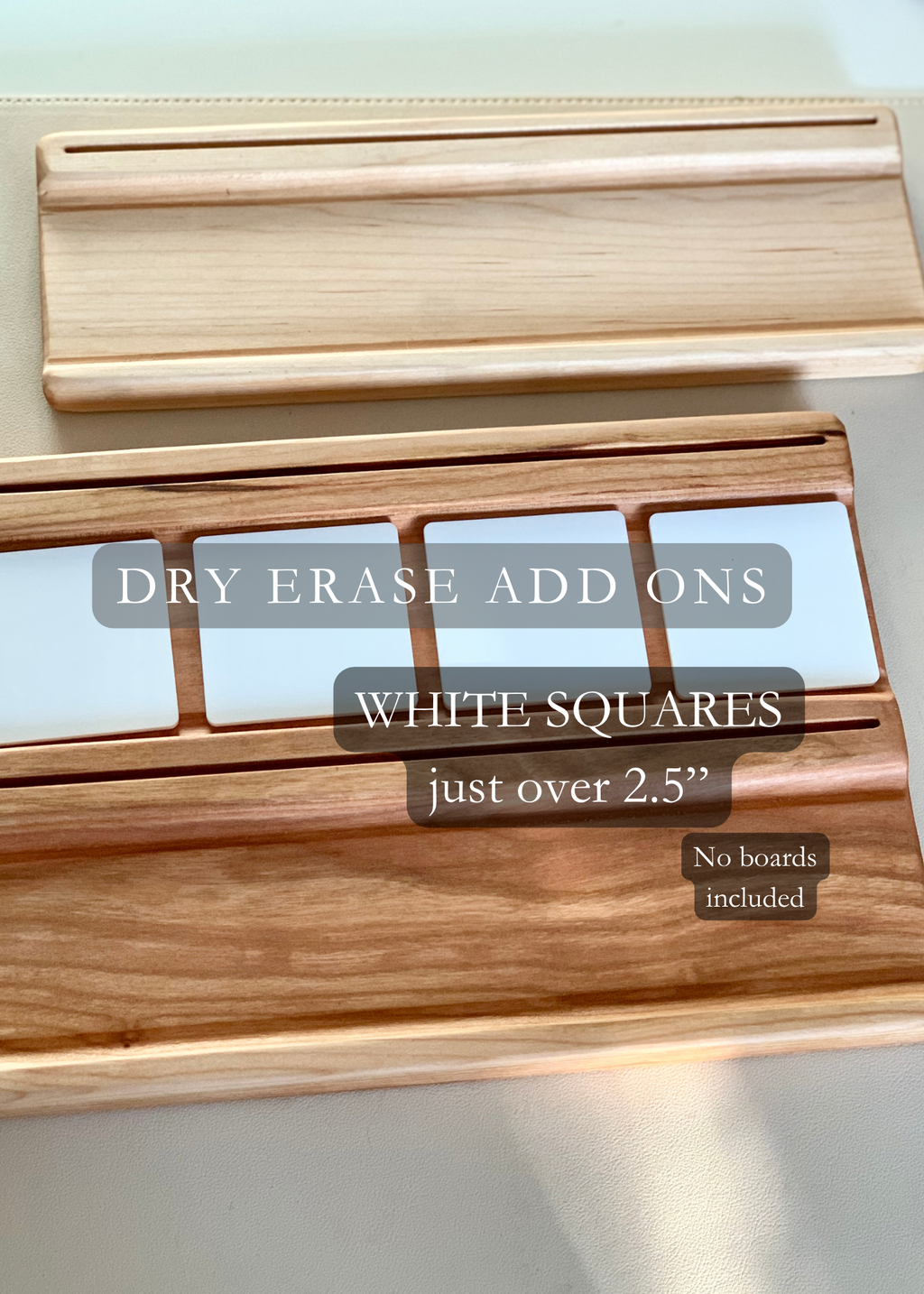 Two wooden dry erase marker holders with slots for white square dry erase add-on pieces on a light surface