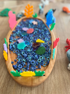 Multipurpose Oval Sensory Tray with textured blue sensory rings, colorful wooden plant shapes around the edge, handcrafted wood tray, homeschool, educational resources.